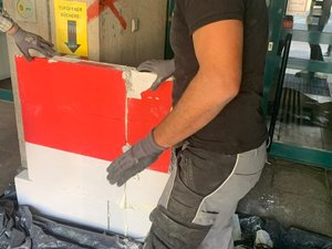 Foto vom Abriss der Mauer: zwei Arbeiter*innen heben einen Teil einer von Rechtsextremen errichteten Mauer weg