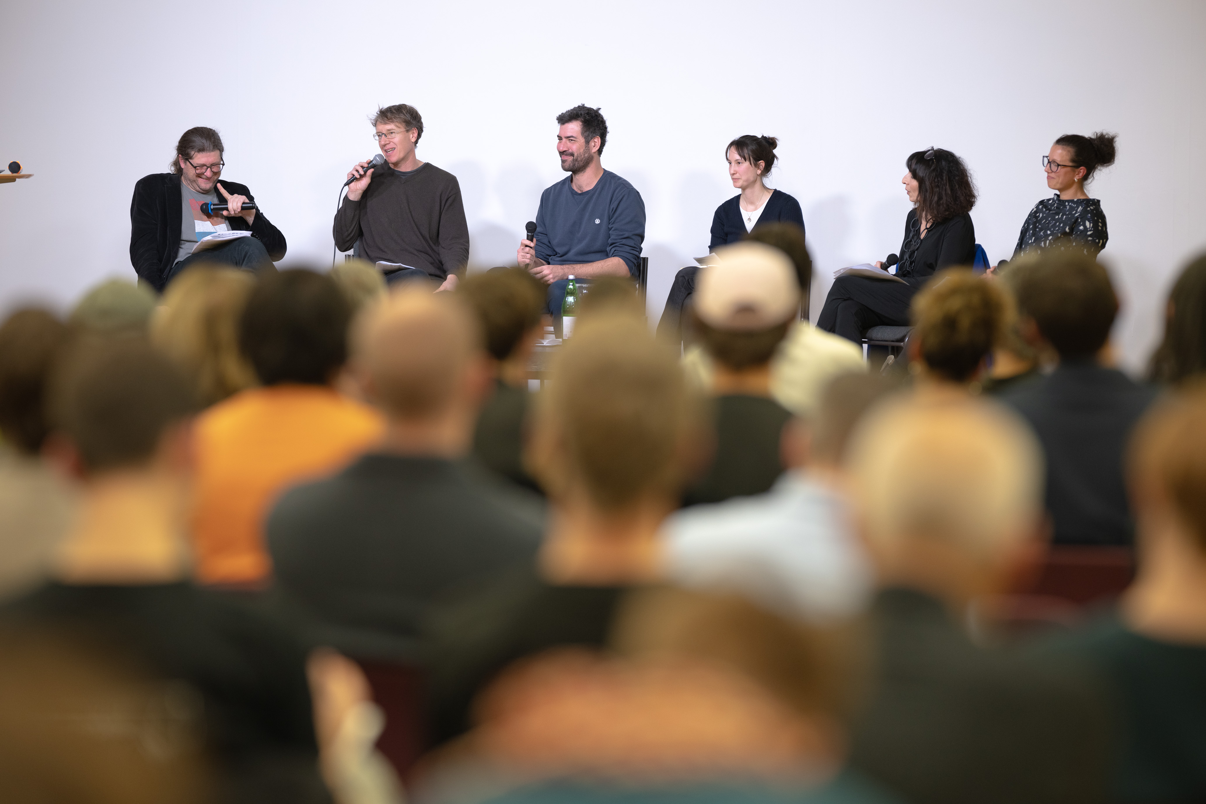 Foto: eSeL.at - Felix Kubitza Die Diskussionsteilnehmer*innen am Podium sitzend, davor (von hinten fotografiert) Teile des Publiums